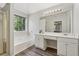 Bathroom featuring a soaking tub, dual sinks, a vanity, and a large window at 3015 Cranbrook Nw Walk, Kennesaw, GA 30144