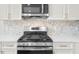 Close up of stainless steel gas range with quartz countertops and white cabinets with gold hardware at 307 Cabinwood Trl, Canton, GA 30115