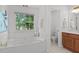 Bright bathroom with a soaking tub with jets, a large window, and wooden cabinets at 3242 Monarch Pine Dr, Peachtree Corners, GA 30071