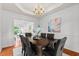 Classic dining area featuring a tray ceiling, chandelier, and an adjacent living room at 3242 Monarch Pine Dr, Peachtree Corners, GA 30071