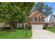 Charming brick home featuring a well-manicured front yard, mature trees, and a two-car garage at 3242 Monarch Pine Dr, Peachtree Corners, GA 30071