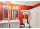A red-themed bathroom featuring a single sink vanity, a standard toilet and a white shower and tub combination at 4467 Pineridge Cir, Atlanta, GA 30338