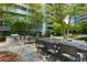 Community outdoor dining area with grill, multiple tables, and seating, surrounded by lush landscaping and a modern building at 950 Nw W Peachtree Nw St # 410, Atlanta, GA 30309