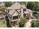 Rear exterior of the home showcasing a covered patio, balconies, and access to the pool area surrounded by lush greenery at 3770 Riverly Trce, Marietta, GA 30067