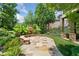 Stone patio featuring a built-in stone fireplace and seating area, surrounded by lush landscaping at 3770 Riverly Trce, Marietta, GA 30067
