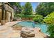 Backyard with a pool, hot tub, and lush landscaping, featuring a stone patio and entertaining area at 3770 Riverly Trce, Marietta, GA 30067