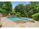 Backyard pool with a basketball hoop and adjacent hot tub, surrounded by greenery and stone patio at 3770 Riverly Trce, Marietta, GA 30067