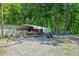 Gravel driveway next to a boat trailer and a carport with a jet ski with woods surrounding the home at 1000 Delta Dr, Canton, GA 30114