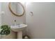 Bathroom with a pedestal sink and a modern round mirror, and a houseplant for decor at 568 Musical Ct, Lawrenceville, GA 30044
