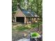 A detached one-car garage with neutral siding and trim, black garage door, and surrounded by lush greenery at 2901 Briscoe Rd, Loganville, GA 30052