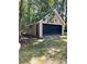 Detached one-car garage features a black garage door and is surrounded by lush greenery and mature trees at 2901 Briscoe Rd, Loganville, GA 30052
