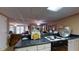 View of kitchen with black countertops, stove top, white cabinets, and open floor plan to living area at 2901 Briscoe Rd, Loganville, GA 30052
