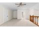Spacious loft area with neutral carpeting, ceiling fan, and natural light from the doorway and staircase at 3228 Turtle Lake Se Dr, Marietta, GA 30067