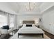 Spacious bedroom with a tray ceiling, decorative chandelier, hardwood floors, and a sitting chair at 3065 Foxhall Overlook, Roswell, GA 30075