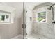 Modern shower with white marble-style tile, glass enclosure, and a window at 1283 Beecher Sw St, Atlanta, GA 30310