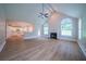 Open-concept living room with fireplace, ceiling fan, light wood floors, and a view into the modern, white kitchen at 157 Hambrick Dr, Stockbridge, GA 30281