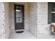 Close up of the front door with glass features and a black mat on a brick facade at 2630 Timler Trce, Snellville, GA 30078