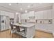 Modern kitchen with white cabinets, stainless steel appliances, large island with seating and hardwood floors at 2630 Timler Trce, Snellville, GA 30078