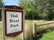 Sign for Oak Road Park with view of greenery and wooden fence at 2630 Timler Trce, Snellville, GA 30078