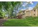 View of a multi-level home with a wooden deck, surrounded by a lush green lawn and mature trees at 3267 Remembrance Trce, Lawrenceville, GA 30044