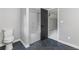 Well-lit bathroom with black tile flooring, a tub-shower combo, and a modern black door at 12995 Bucksport Dr, Roswell, GA 30075