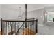 Upstairs hallway with wood and metal banister, chandelier, and gray carpet at 12995 Bucksport Dr, Roswell, GA 30075