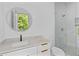 Bright bathroom features a modern vanity, round mirror, and glass-enclosed shower at 157 Shadburn Ferry Rd, Buford, GA 30518