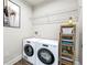Functional laundry room with modern washer, dryer, storage shelves, and a wire rack for supplies at 791 Belrose Dr, Smyrna, GA 30080
