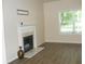 Living room featuring a classic fireplace with white mantel, a large window, and hardwood flooring at 4750 Crinklepoint Ct, Douglasville, GA 30134