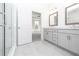 Bright bathroom featuring gray double vanity cabinets, framed mirrors, and doorway to bedroom at 1005 Crown Oak St # 44, Johns Creek, GA 30022