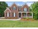Stately brick home featuring a covered front porch and well-manicured lawn at 2525 Millwater Xing, Dacula, GA 30019