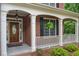 Inviting front porch with brickwork, white columns, and a decorative wood front door at 2525 Millwater Xing, Dacula, GA 30019
