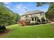 Exterior view of the home showcasing a spacious lawn, large deck, mature landscaping, and elegant architectural details at 340 Old York Rd, Johns Creek, GA 30097