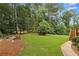 Expansive backyard features a manicured lawn, mature trees, and an inviting fire pit area at 340 Old York Rd, Johns Creek, GA 30097