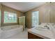 Bright bathroom featuring a soaking tub, double sinks, and views of the wooded landscape outside at 2563 Creek Ter, Snellville, GA 30078