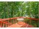 A red wood deck with a table and beautiful green tree views at 2563 Creek Ter, Snellville, GA 30078