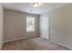 This bedroom features neutral walls, carpet flooring, a window, and a white door at 4164 Little Nw Spgs, Kennesaw, GA 30144
