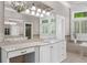 Bright bathroom featuring a large mirror, custom vanity, garden tub and large windows at 9005 Old Southwick Pass, Alpharetta, GA 30022
