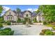 Daytime view of a charming two-story home with lush landscaping and a circular driveway with fountain at 9005 Old Southwick Pass, Alpharetta, GA 30022