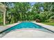 A rectangular swimming pool is surrounded by a tile patio and lush greenery creating a private backyard oasis at 9005 Old Southwick Pass, Alpharetta, GA 30022