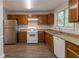 Well-lit kitchen with stainless steel refrigerator, modern white appliances, and wooden cabinets at 847 Ashley Ln, Stone Mountain, GA 30087