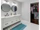 Bright bathroom with double vanity sinks, white cabinets, matte black hardware, and a view into a walk-in closet at 1740 Dodson Sw Dr, Atlanta, GA 30311