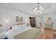 Bright bedroom with a modern chandelier, white walls, and ensuite bathroom with wooden flooring at 201 Tweed Ct, Sugar Hill, GA 30518