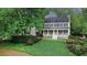 Charming two-story home featuring a welcoming front porch, white siding, black shutters and lush landscaping at 201 Tweed Ct, Sugar Hill, GA 30518