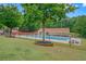 Community pool area with a large pool, picnic tables, and mature trees in a landscaped setting at 201 Tweed Ct, Sugar Hill, GA 30518