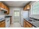 Efficient kitchen showcasing white appliances, wood cabinets, and a view to the adjacent room at 9119 Woodgreen Way, Jonesboro, GA 30238