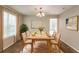 Bright dining room with a wooden table set for six, complemented by modern artwork and large windows at 9542 Canvasback Ct, Jonesboro, GA 30238