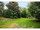Serene backyard with lush green lawn, mature trees, and a charming wooden fence at 1023 Spruce Creek Ln, Lawrenceville, GA 30045