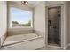 Bright bathroom featuring a soaking tub, walk-in shower, and large window at 1023 Spruce Creek Ln, Lawrenceville, GA 30045