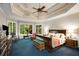 Primary bedroom with tray ceiling, carpet, and a sitting area by the bay window at 1023 Spruce Creek Ln, Lawrenceville, GA 30045